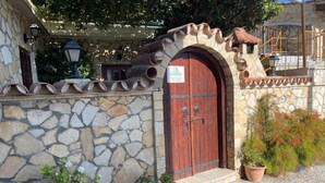 Un bâtiment en pierre avec une porte en bois, des plantes en pot et une enseigne.