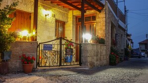 A stone building with a wooden porch, a metal gate, and potted plants. - Omodos Village Houses (Omodos)