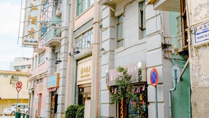 A multi-story building with balconies, a no parking sign, and a storefront with a sign in a foreign language. - Hou Kong Hotel (Macau)