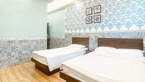 A hotel room with two beds, a wooden floor, and a patterned wall. - Hou Kong Hotel (Macau)