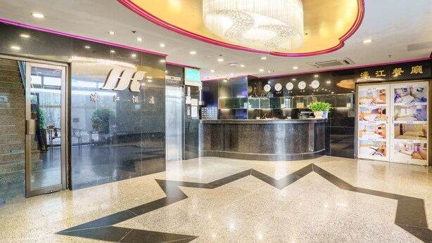A hotel lobby with a reception desk, a chandelier, and a clock on the wall. - Hou Kong Hotel (Macau)