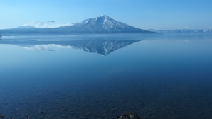A calm lake with a mountain reflected in the water. - Guest House Shikotsu Kamui - Hostel (Chitose)
