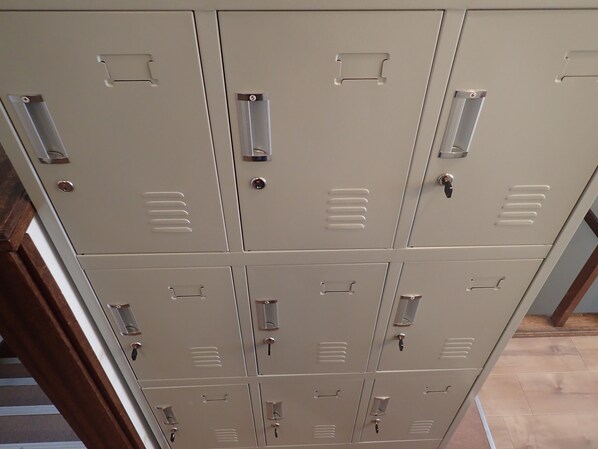 Una hilera de taquillas beige de metal, con manijas y cerraduras, probablemente para guardar objetos en un espacio público o compartido.
