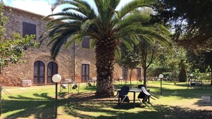 A courtyard with stone walls, palm trees, and outdoor seating.
