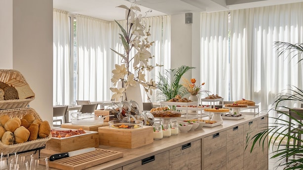 Un bufé de desayuno con diversas opciones de comida y una planta orquídea decorativa.