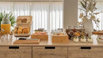 A breakfast buffet with bread, pastries, and various food items.