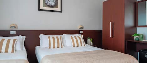Habitación de hotel con dos camas, un cuadro enmarcado en la pared y un armario con espejo.