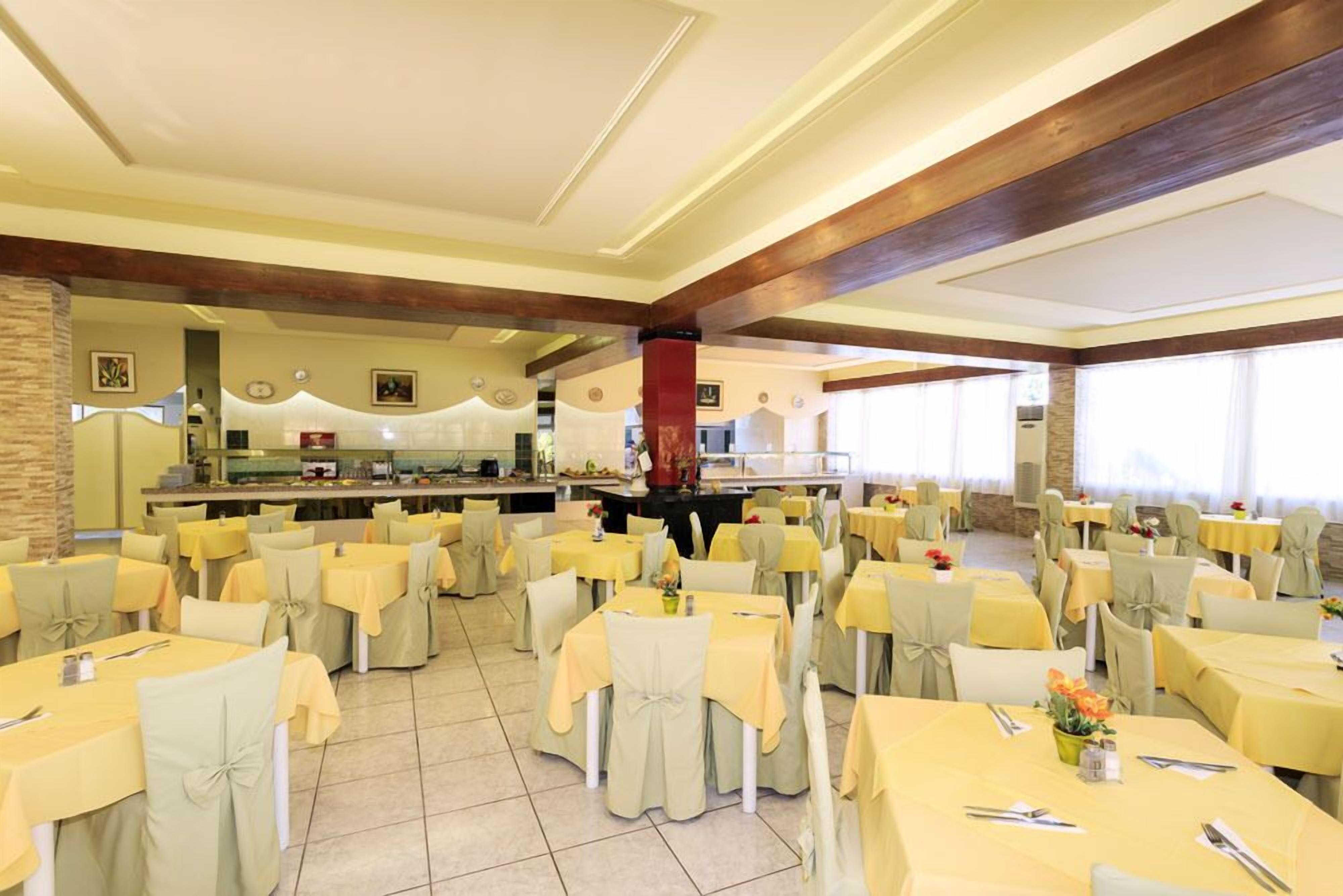Un comedor amplio con varias mesas y sillas, un bufé central y vista al área de la cocina.