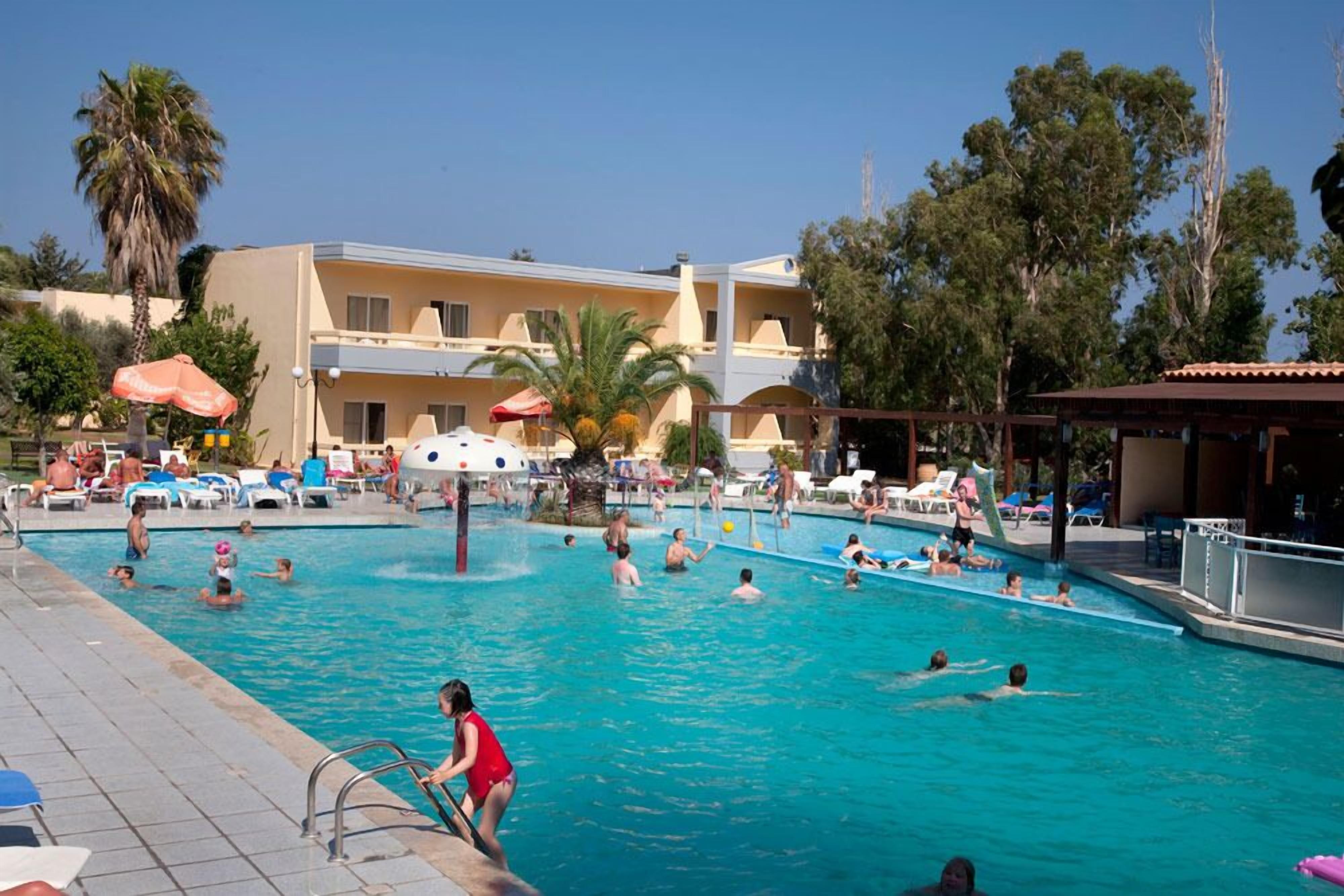 A swimming pool area with multiple pools, lounge chairs, and umbrellas.