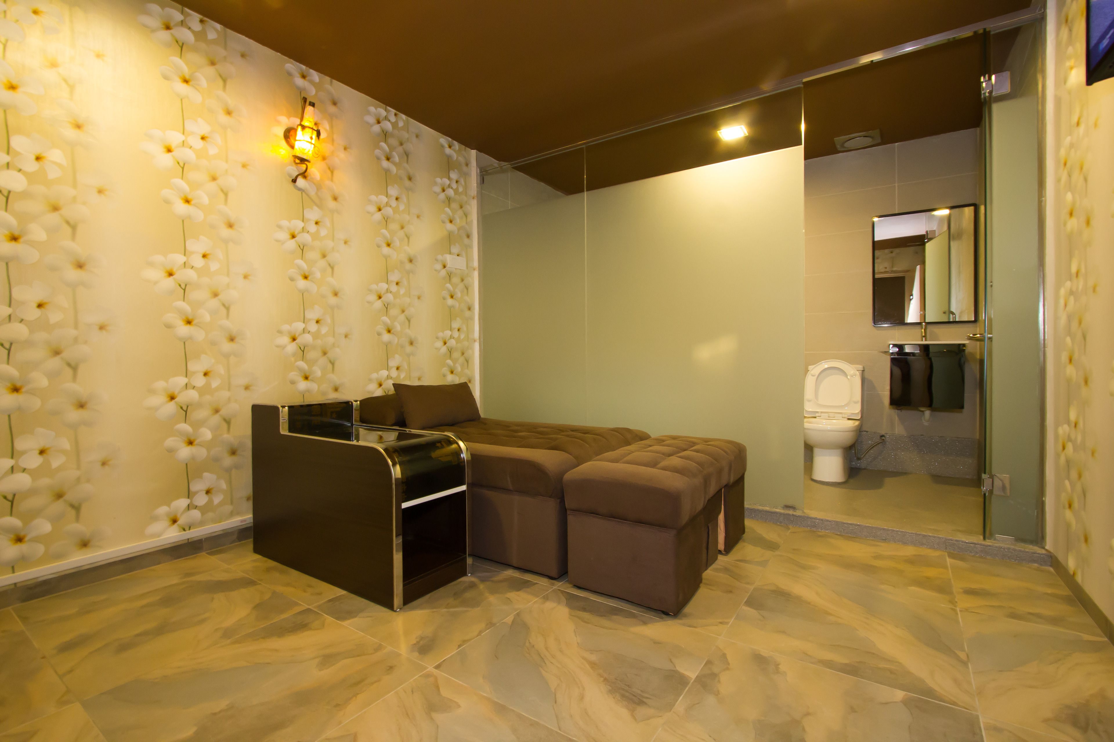 A modern bathroom with a marble floor, a large mirror, a toilet, and a bench.