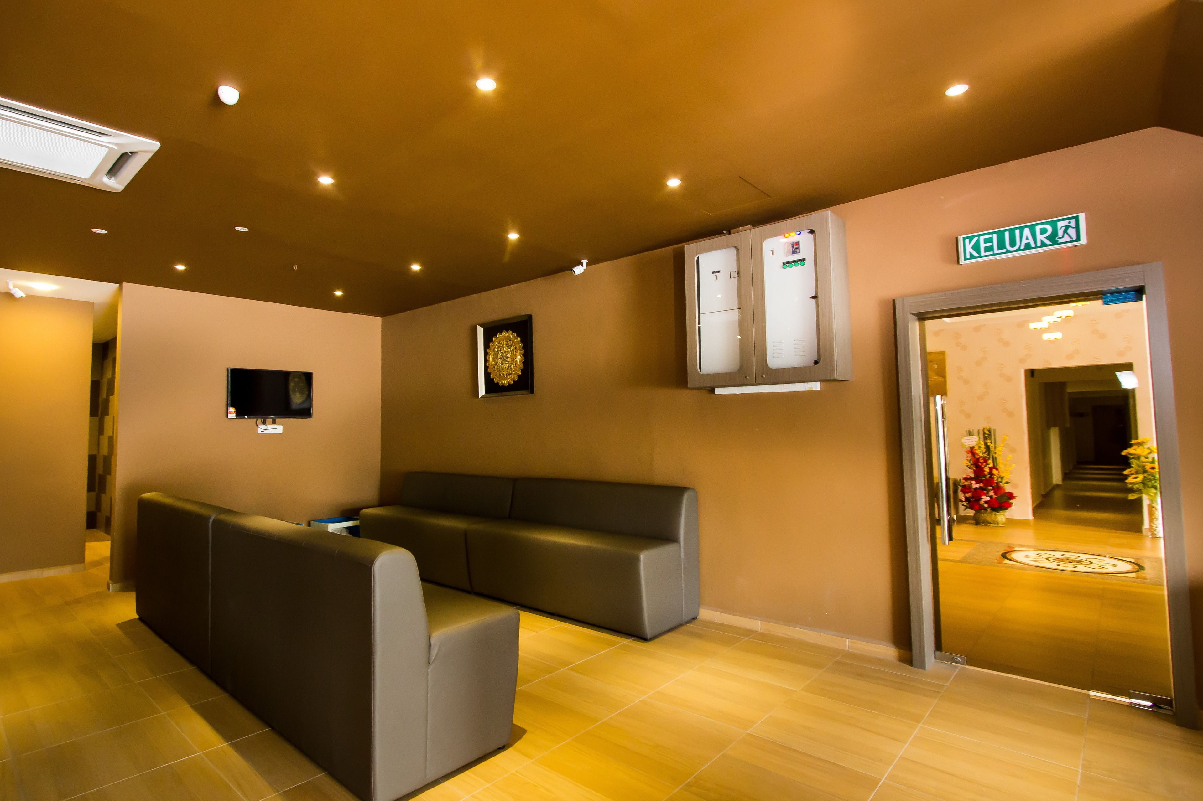 A modern lobby with a sofa, a flat-screen TV, a ceiling-mounted air conditioner, and a sign reading "KELUAR".
