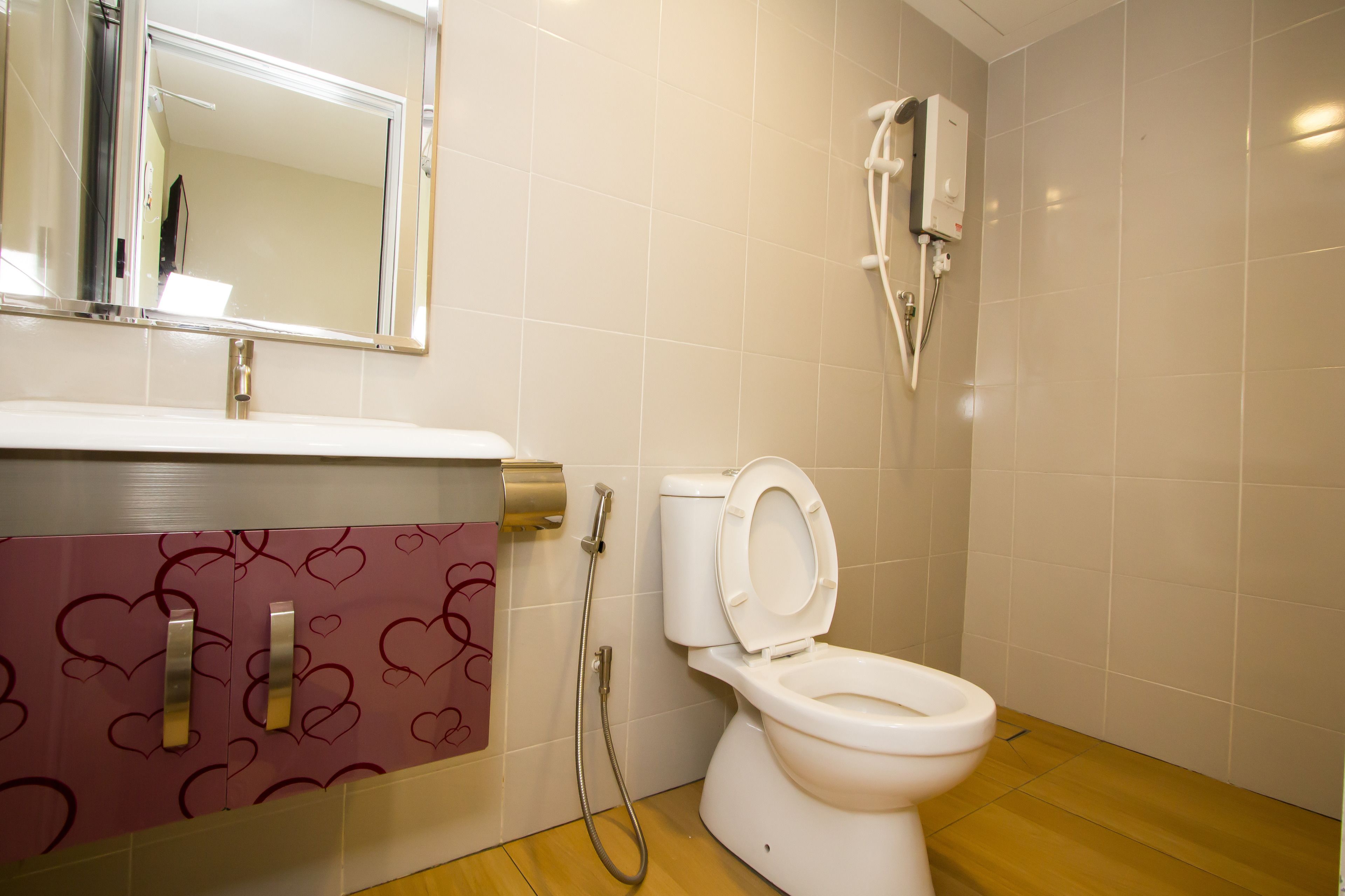 Een badkamer met een wit toilet, een douche en een spiegel boven de wastafel.