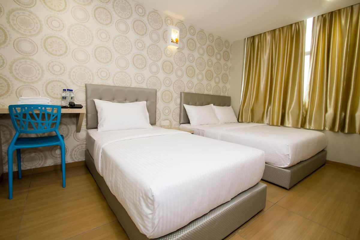Ein Hotelzimmer mit zwei Betten, einem Schreibtisch mit Stuhl und einem Wandpapier mit Muster.
