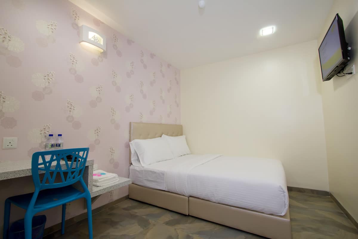 Ein Schlafzimmer mit Bett, Schreibtisch, Stuhl und einem an der Wand befestigten Fernseher.