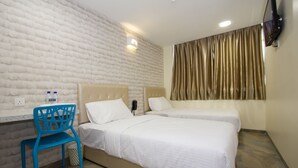 Een hotelkamer met twee bedden, een blauwe stoel, een witte muur en een aan de muur bevestigde televisie.