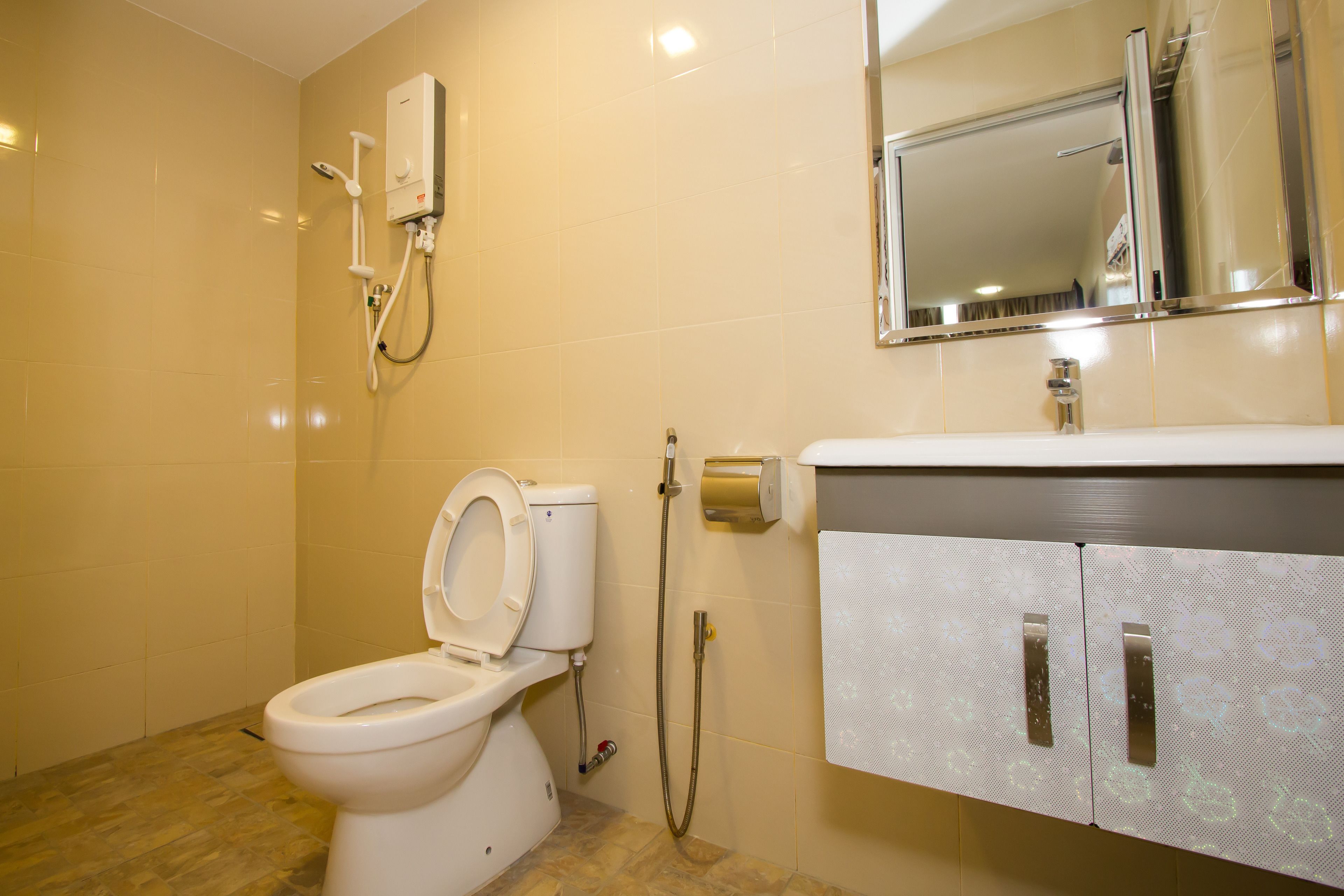 A bathroom with a toilet, a shower unit, and a sink with a cabinet.