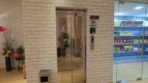 Een lift met een glazen deur, een rookverbodsgeeltje en een digitaal scherm dat het verdiepingsnummer toont.