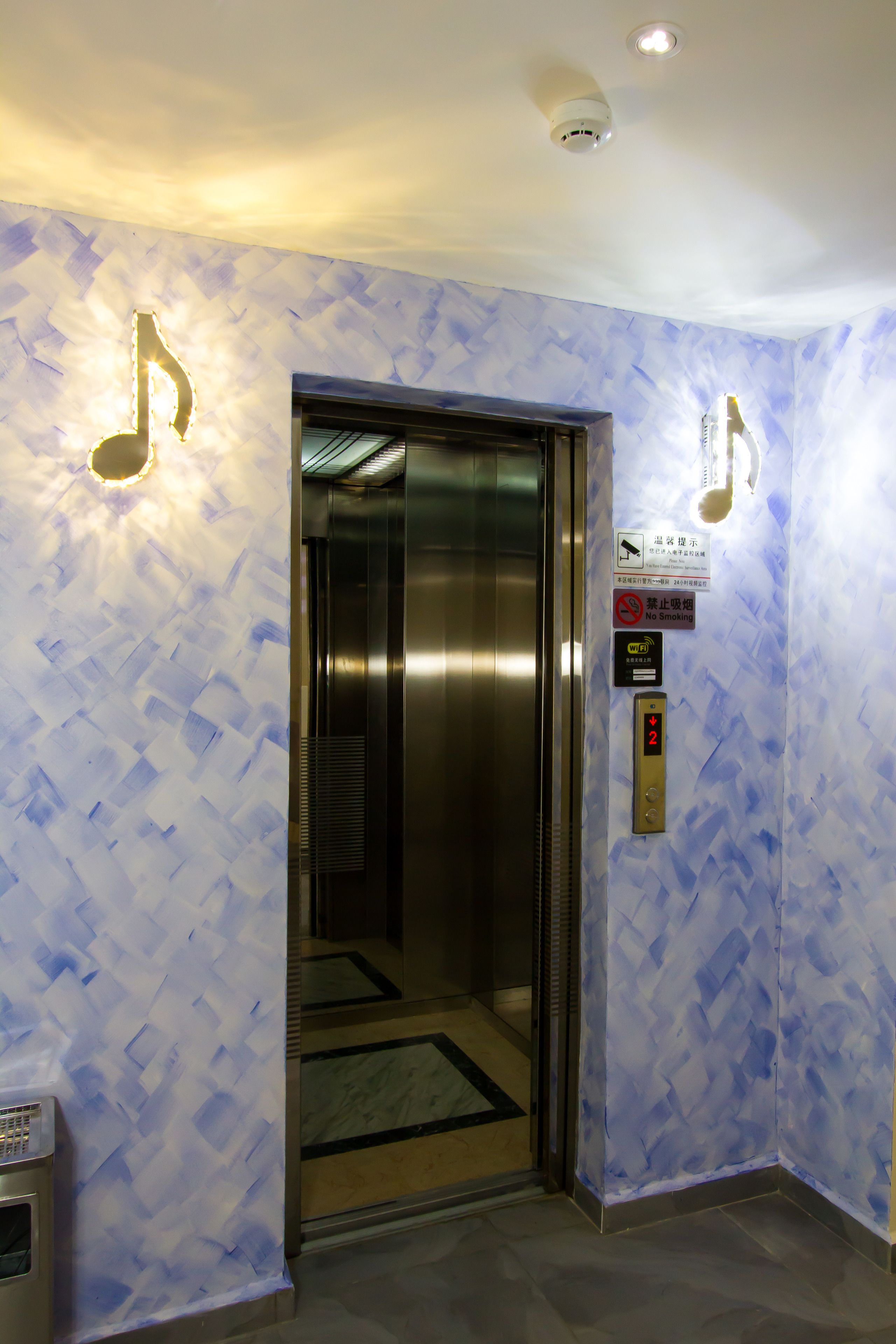 Un ascensor con un cartelito en la pared que indica prohibido fumar y un indicador de planta que muestra el nivel 2.