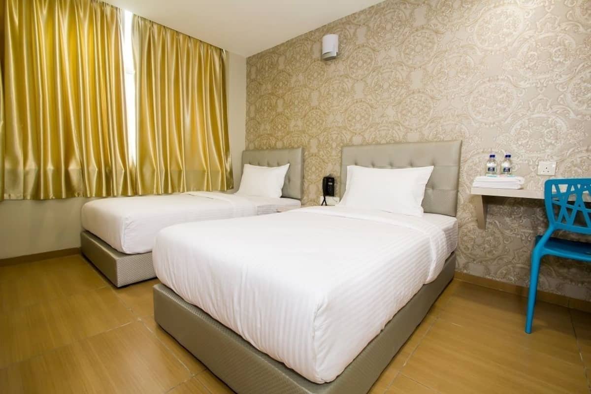 Ein Hotelzimmer mit zwei Betten, einem Schreibtisch, einem Stuhl und einer Wand mit Muster.