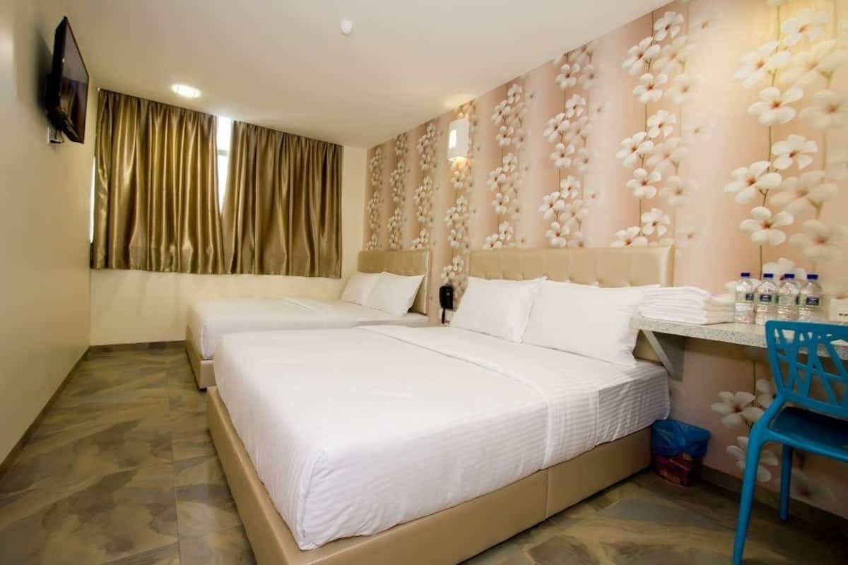 Ein Hotelzimmer mit zwei Betten, einem Schreibtisch mit Stuhl und einer mit Blumen verzierten Wand.