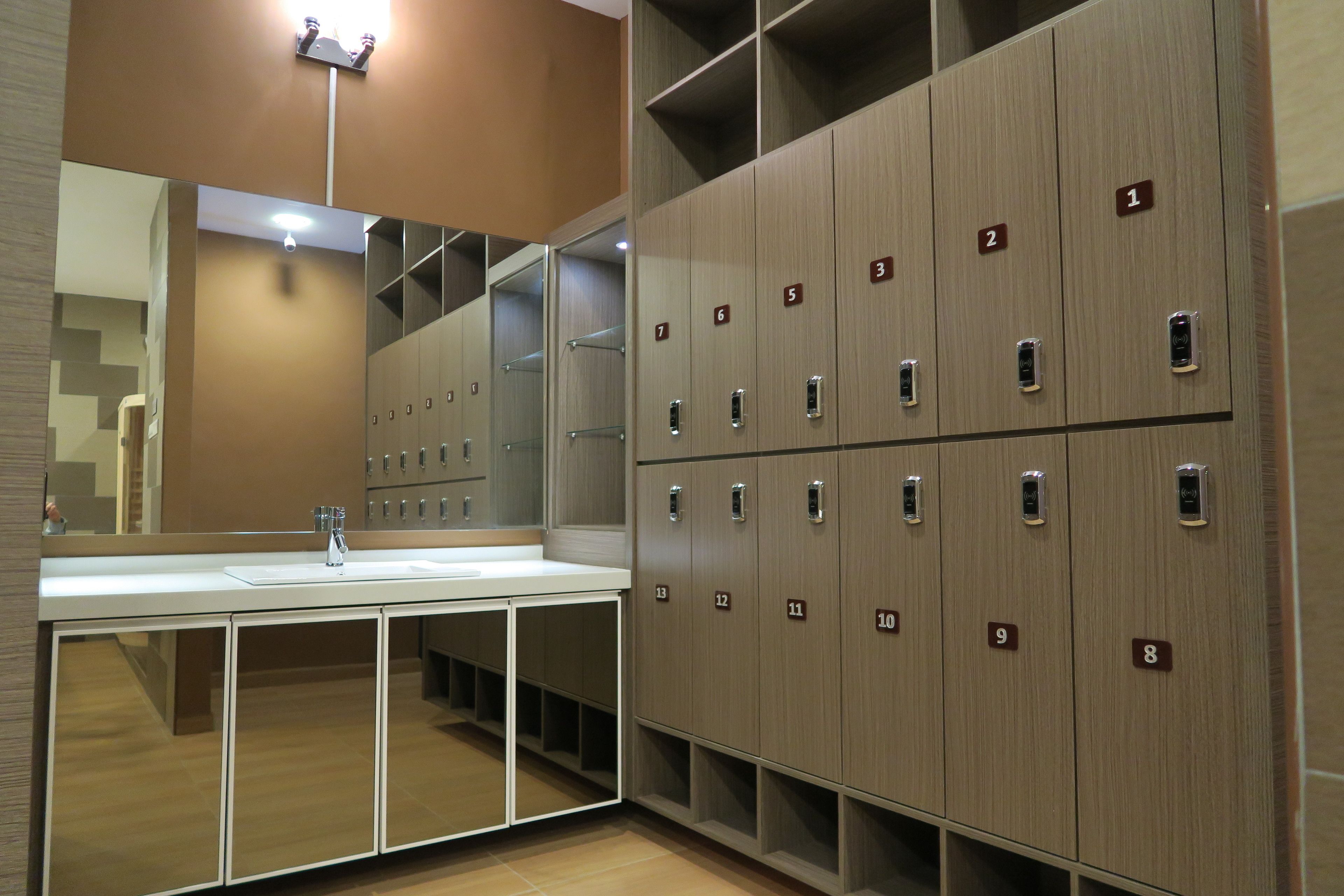 A modern bathroom with a large mirror, a sink, and wooden lockers numbered 1 to 13.