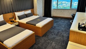 Habitación de hotel con dos camas, un escritorio y un ventanal amplio con vistas a la ciudad.