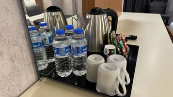 Una bandeja con botellas de agua, un hervidor y tazas de café sobre una encimera de hotel.
