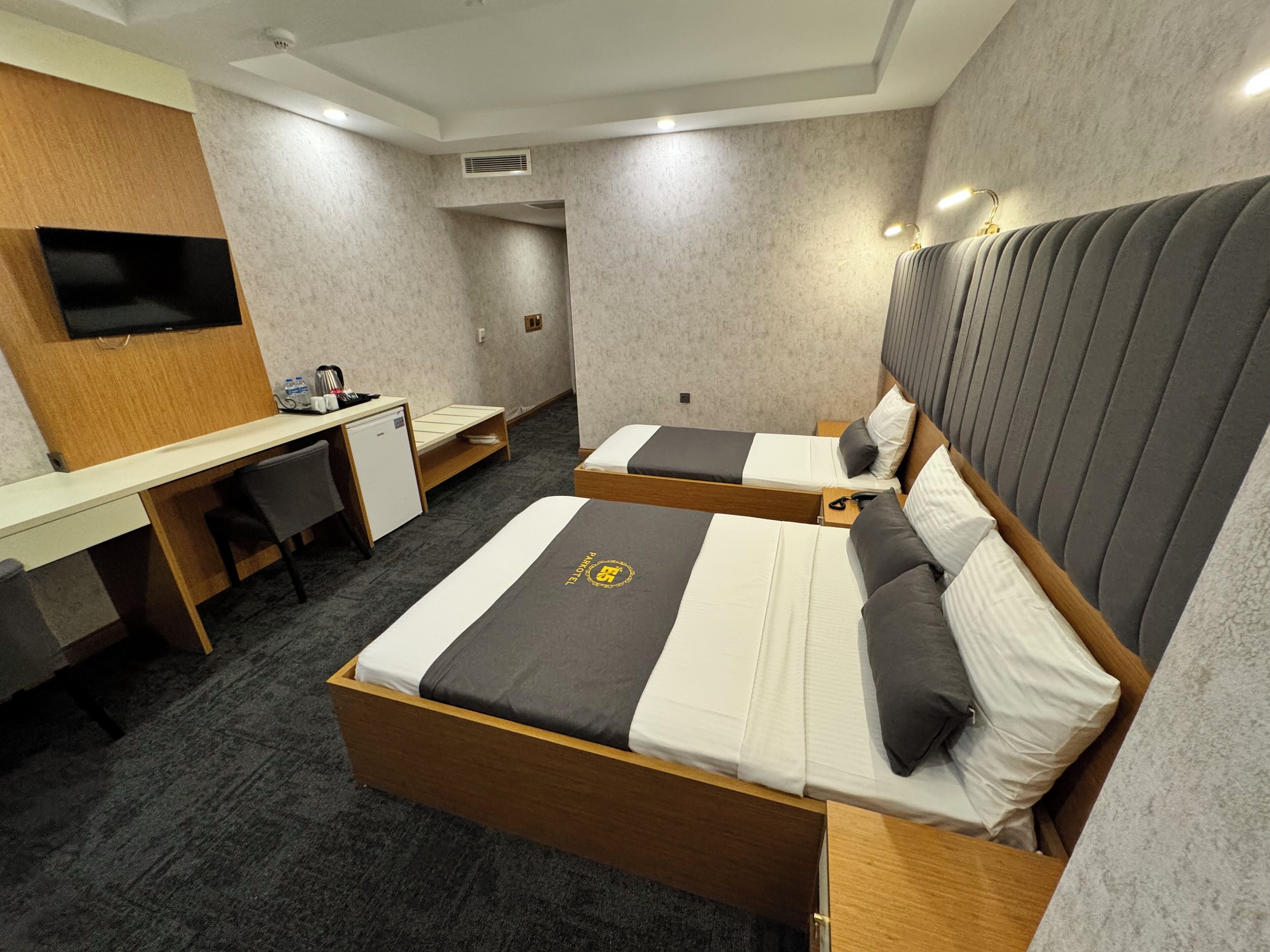 A hotel room with two beds, a desk, a television, and a minibar.