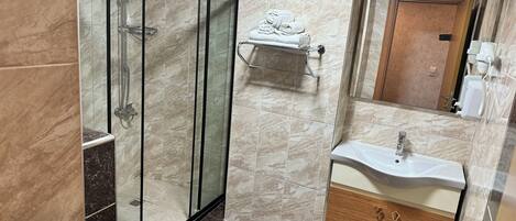 A modern bathroom with a glass-enclosed shower, a toilet, a sink with a vanity, and a towel rack.