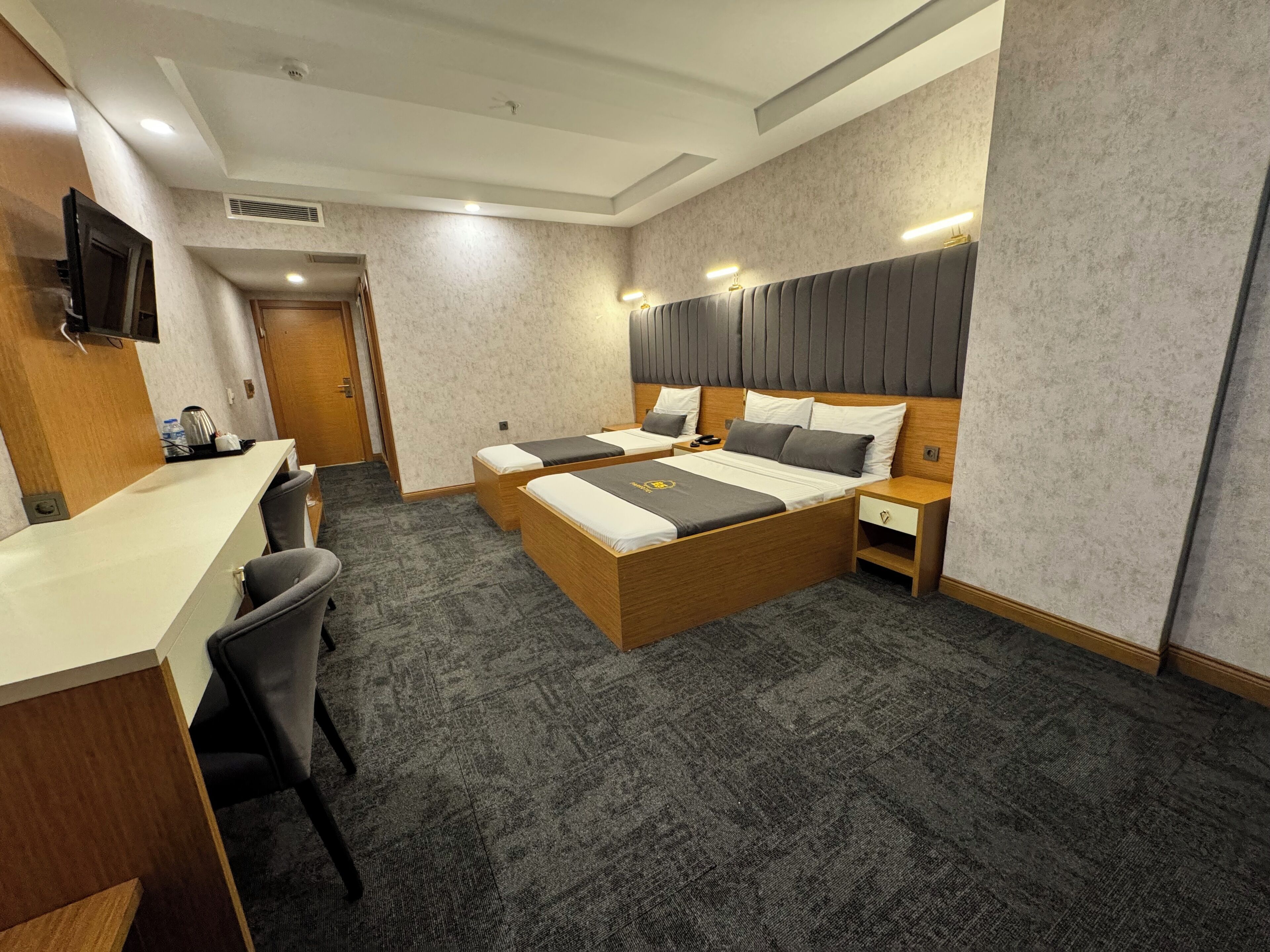 A hotel room with a bed, desk, chairs, and a TV.