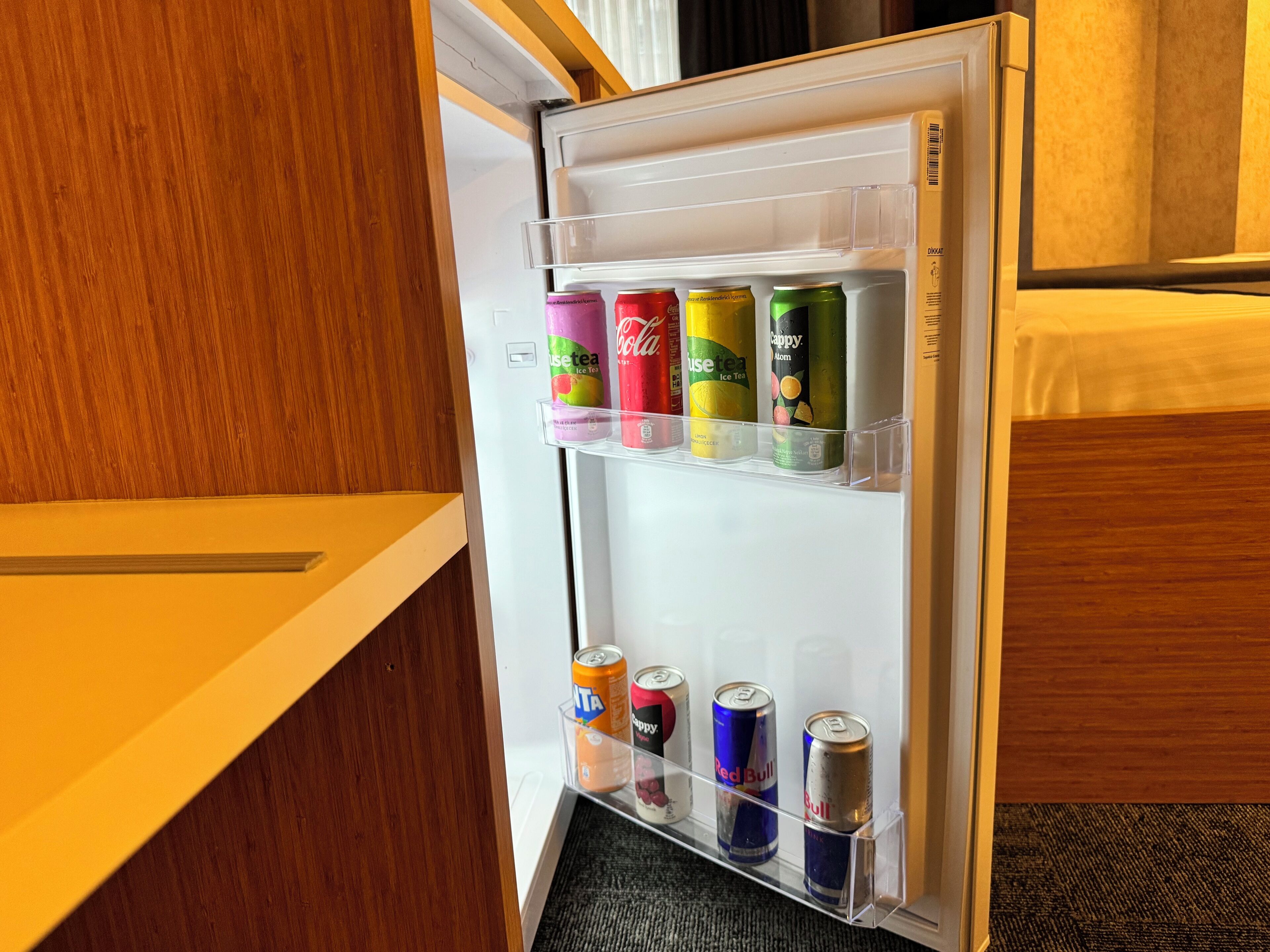 A refrigerator with multiple shelves containing various beverages including cans and bottles.