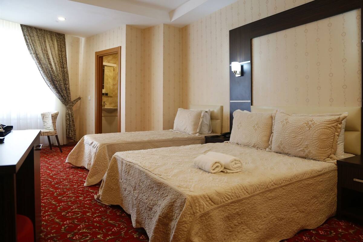 A hotel room with two beds, a desk, a chair, and a bathroom visible through an open door.