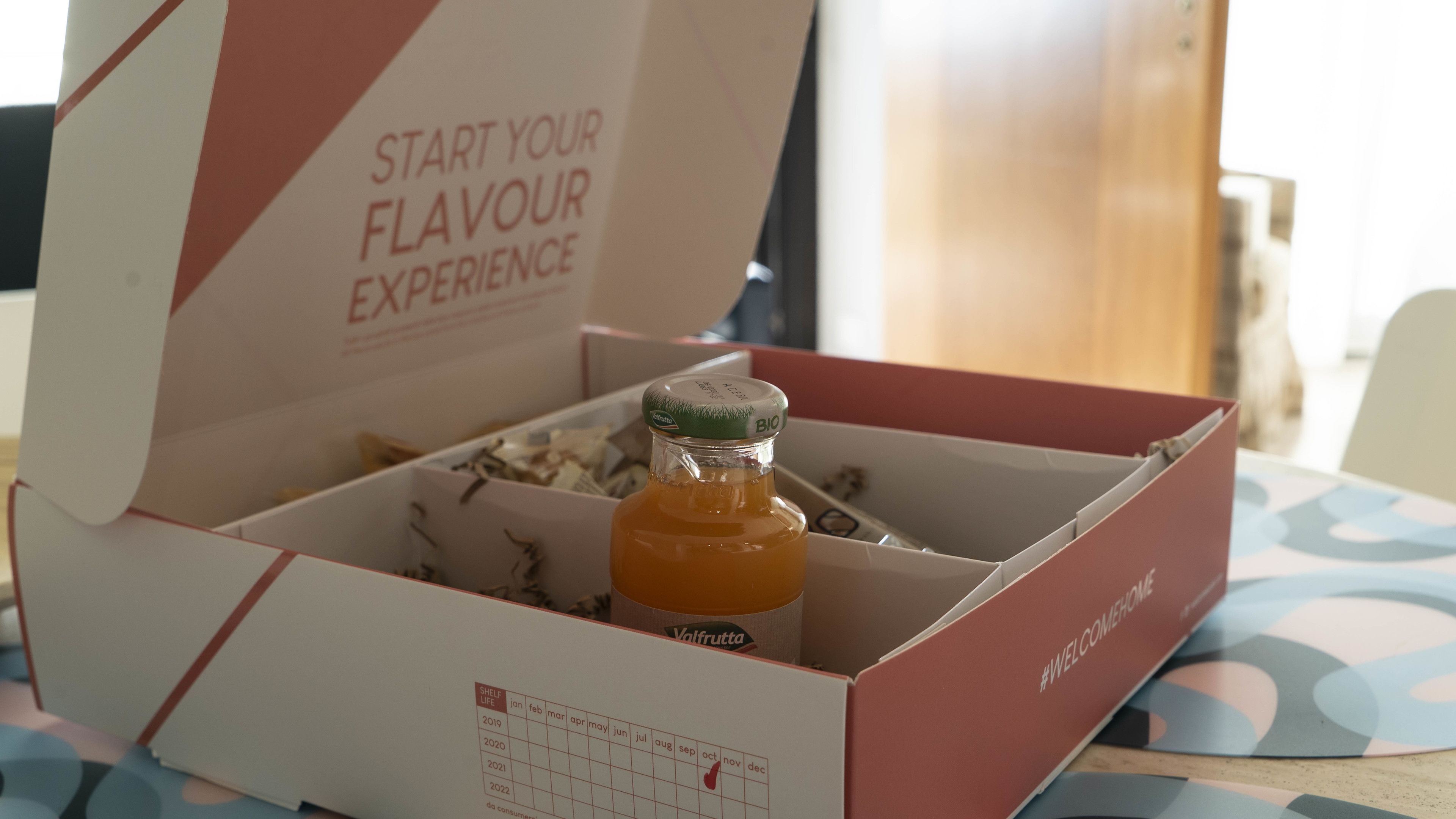 Een open doos met een fles Valfrutta-sap, een kalender en een bericht dat je uitnodigt om je smaakervaring te beginnen.