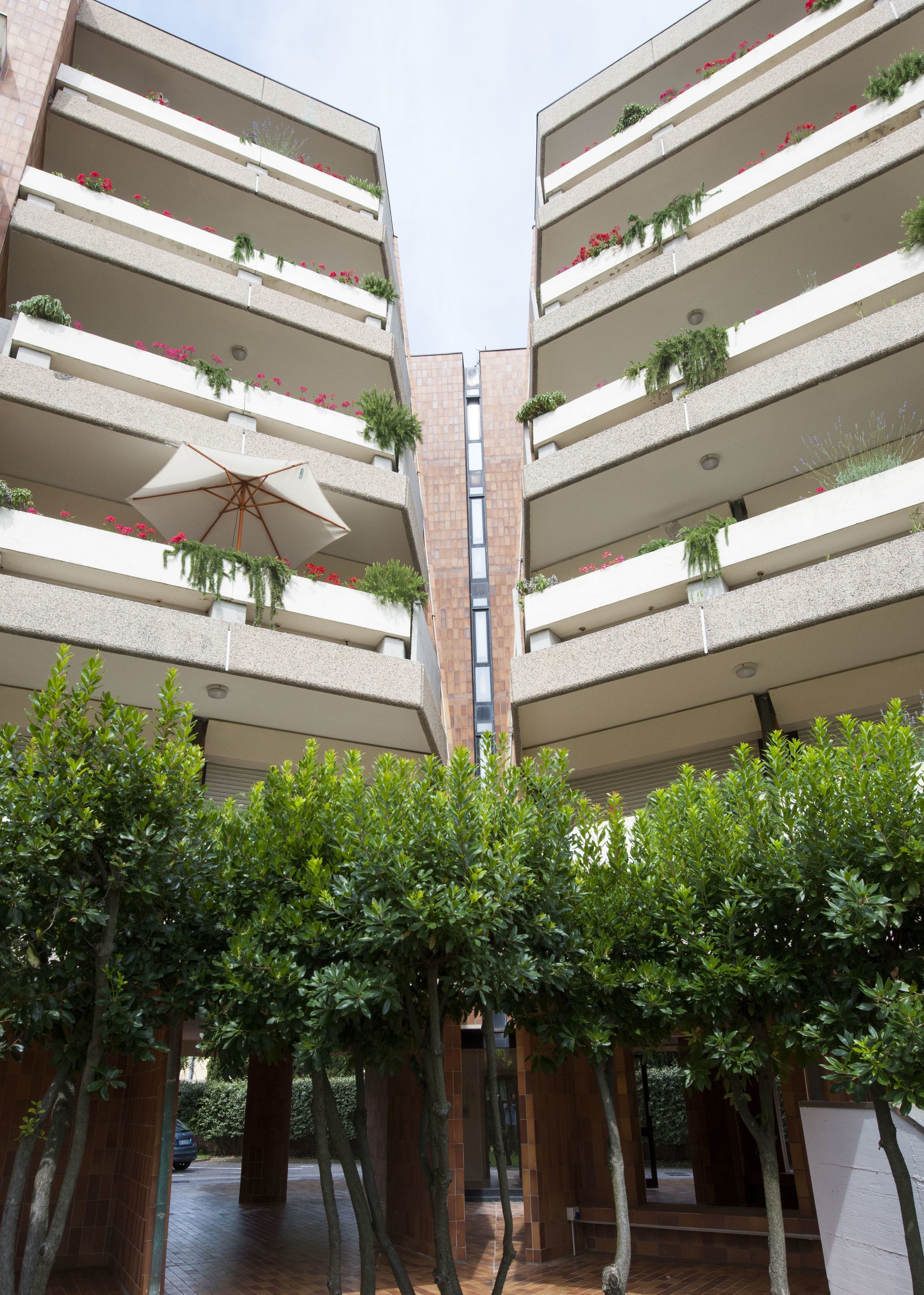 Un edificio moderno con varios balcones, cada uno decorado con plantas y flores.
