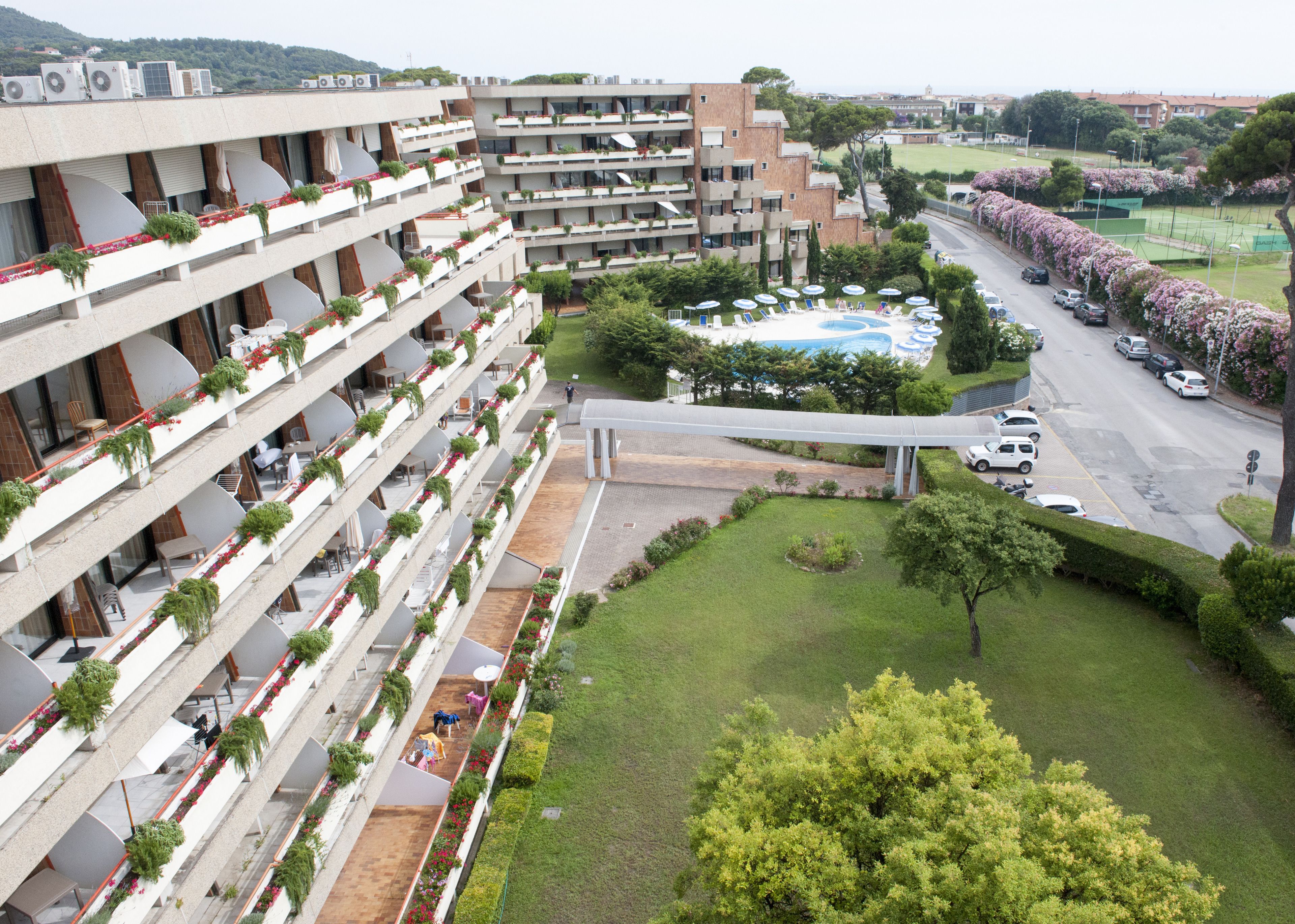 Un hotel de varios pisos con balcones, piscina y zona de estacionamiento.