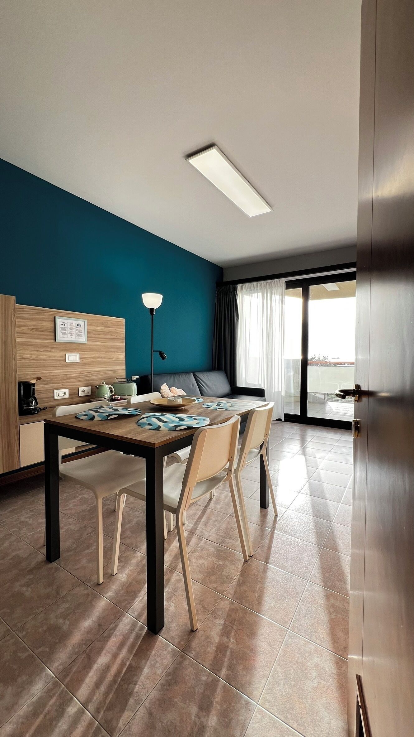 Ein modernes Hotelzimmer mit Essbereich, einer Couch, einer Kaffeemaschine und Blick ins Freie.