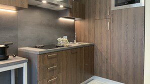 A compact kitchen with wooden cabinets, a built-in microwave, and a countertop with a kettle and a coffee maker. - Suites Marilia Apartments (Livorno)