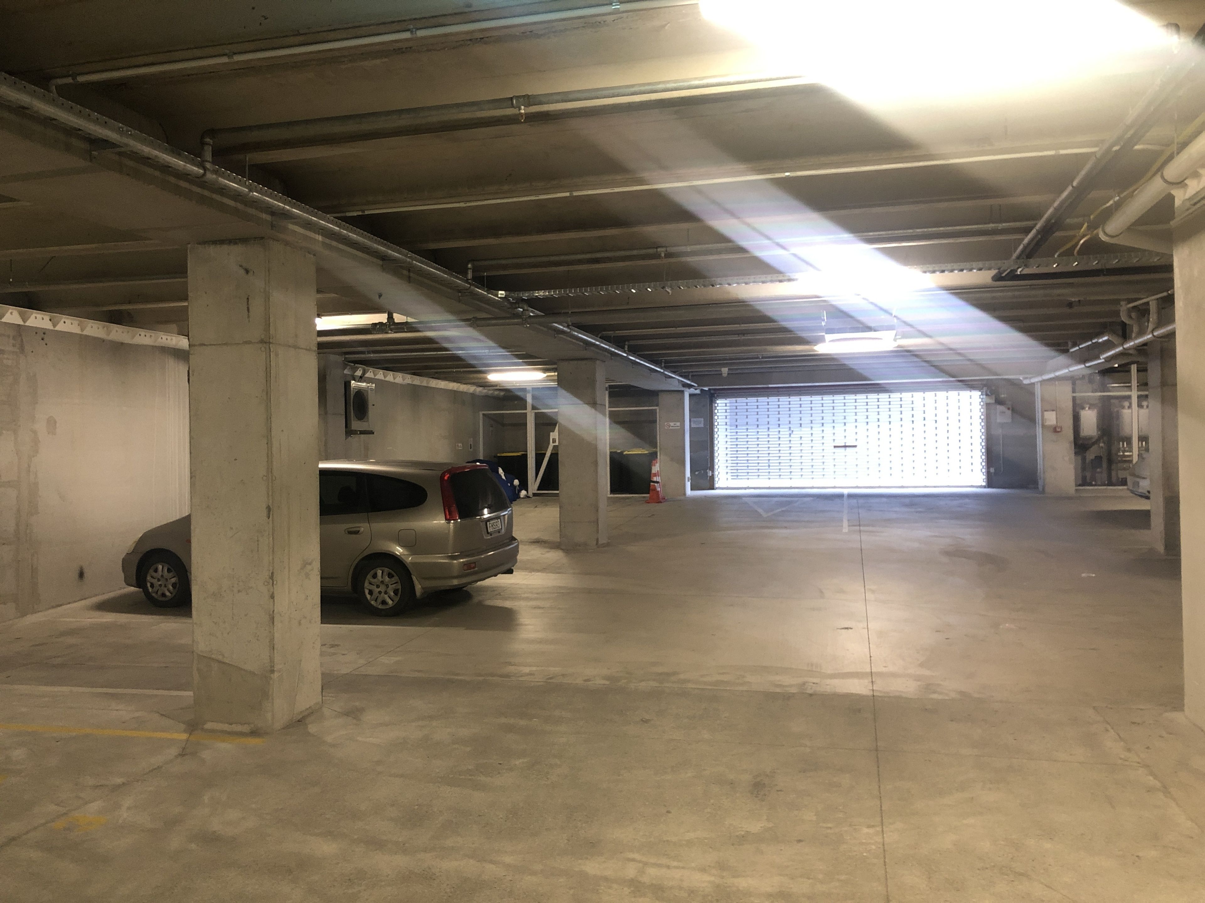 Un garaje con pilares de concreto, un coche y una puerta de garaje.