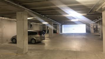 Un garaje con pilares de concreto, un coche y una puerta de garaje.