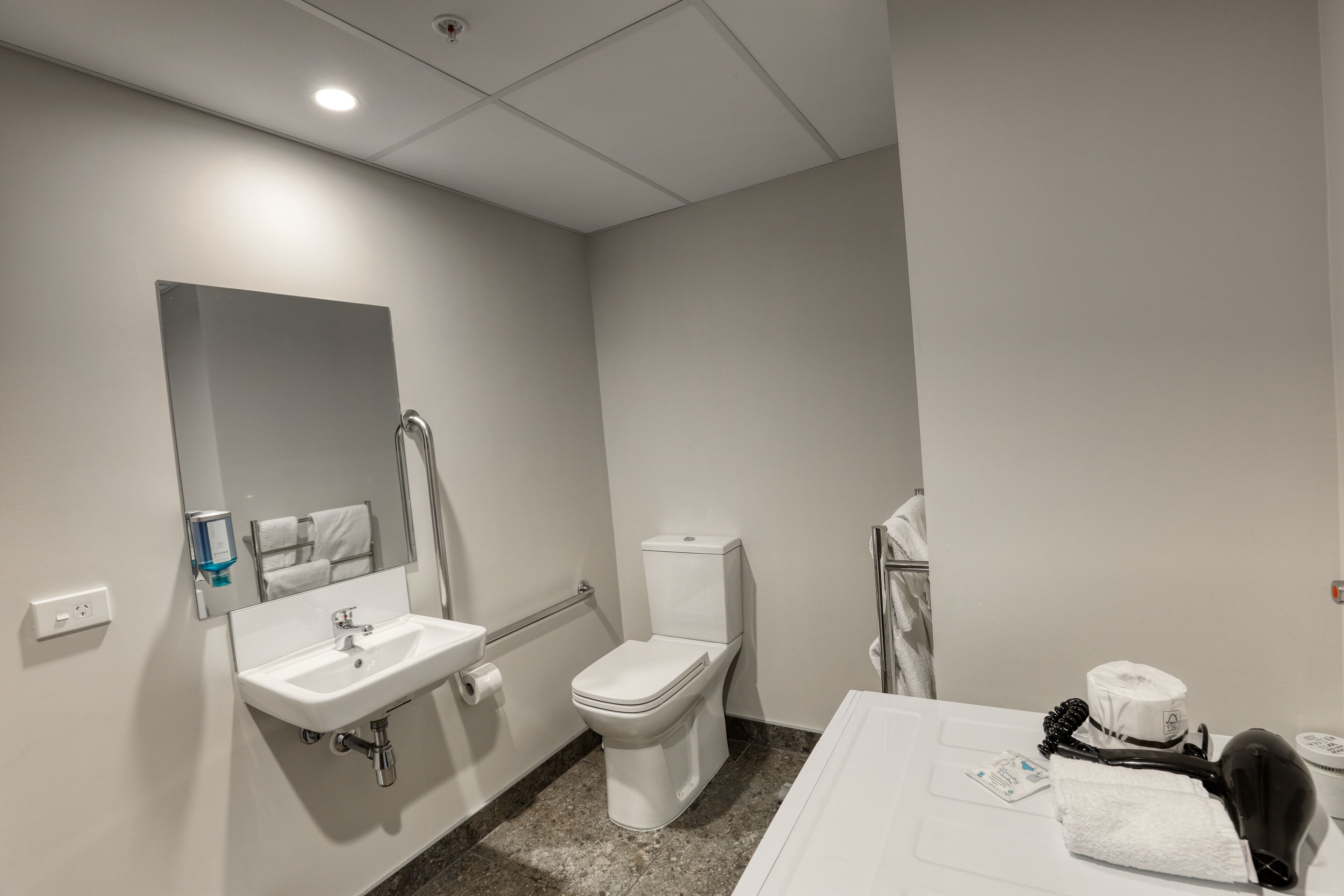 A bathroom with a sink, toilet, and mirror.