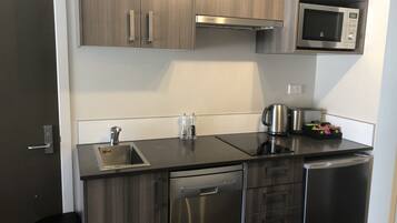 A compact kitchen with a dishwasher, a microwave, and a kettle.