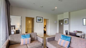 A modern living room with two sofas, a dining area, and a kitchen in the background.