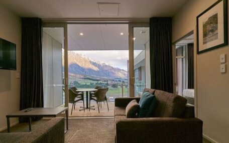 A hotel room with a large sliding glass door leading to a balcony with a mountain view.