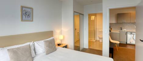 Une chambre d’hôtel avec un lit, une table de chevet, une lampe et un tableau encadré au mur.