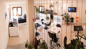 A hotel reception area with a reception desk, seating area, and a dining space. - Xenia Hotel (Villasimius)