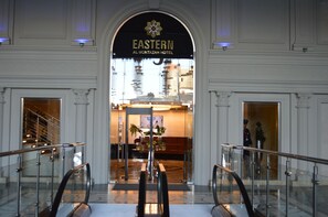 La entrada al Hotel Al Montazah Oriental, con un arco monumental, un mostrador de recepción y un ascensor de cristal.