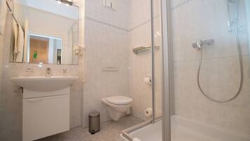 A modern bathroom with a sink, toilet, and glass-enclosed shower.