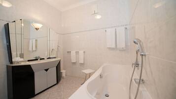 Un baño moderno con una bañera grande, un tocador con espejo y dos toalleros.