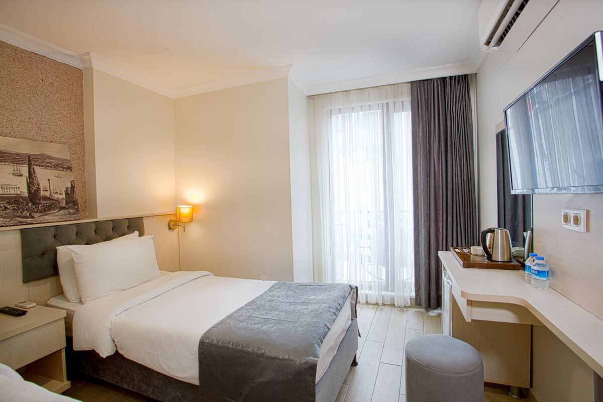 A hotel room with a bed, bedside table, desk, and a television.