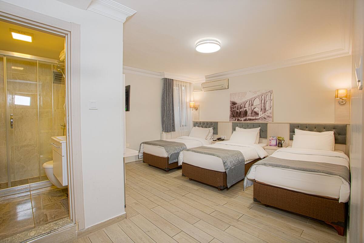 A hotel room with two beds, a bathroom, and a shower.